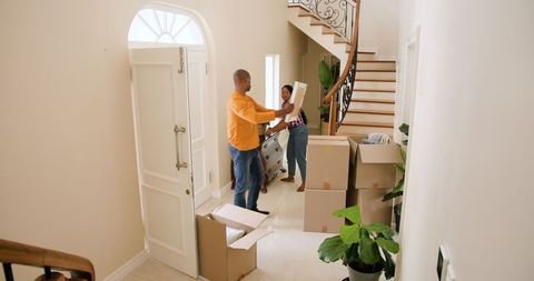 Happy Couple Organizing in New Home Entryway with Boxes