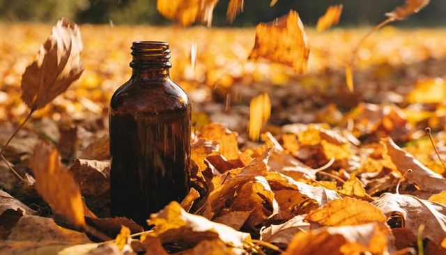 Amber glass bottle glowing in autumn sunlight among falling maple leaves and foliage