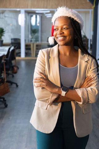 Smiling african american manager wearing santa hat in contemporary open-plan office