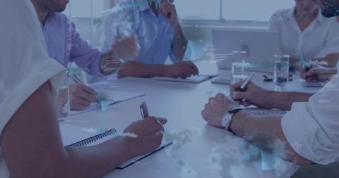 Business team brainstorming and note-taking at meeting table with digital data overlays
