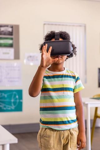 African american child exploring virtual reality in classroom adjusting headset