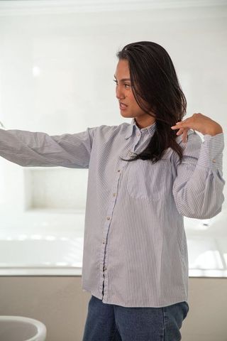 Asian Woman Adjusting Hair in Minimalist Bathroom Setting