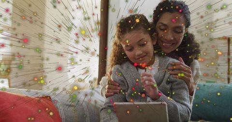 Mother and daughter holding tablet showing colorful augmented reality learning at home