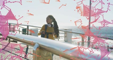 Young woman riding kick scooter on sunlit pier with pink geometric network overlay