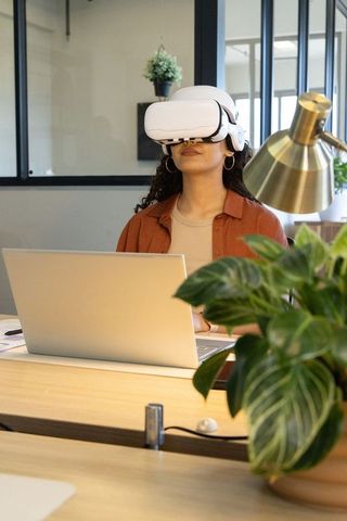 Young professional using virtual reality headset at modern office desk with laptop