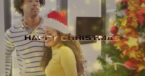 Smiling couple celebrating warm cozy christmas at home with santa hat and festive tree