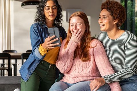 Diverse Women Enjoying Smartphone in Modern Living Space
