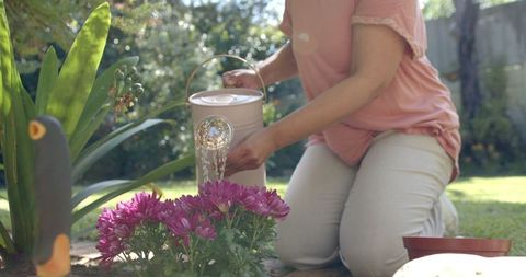 Senior Woman Watering Flowers in Sunlit Garden