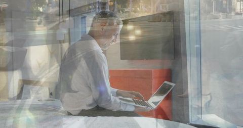 Reflective Mature Man at Laptop in Urban Bedroom Setting