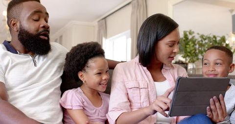 African American Family Enjoying Time Together on Couch with Tablet