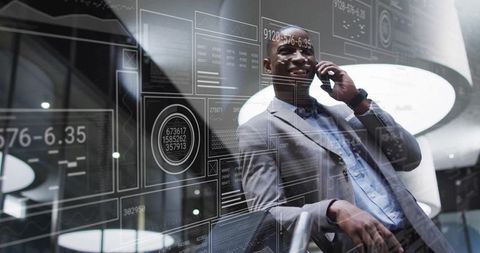 Executive leaning on glass rail using smartphone with futuristic data interface in lobby