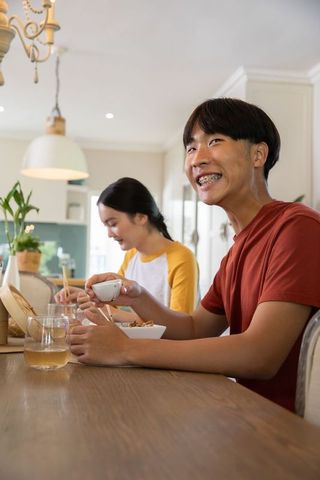 Asian Friends Enjoying Dinner with Chopsticks in Kitchen