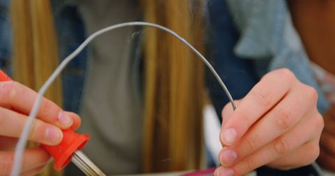 Hands conducting science experiment with heated wire