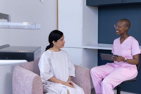 African american nurse consulting with hispanic patient using tablet in modern clinic