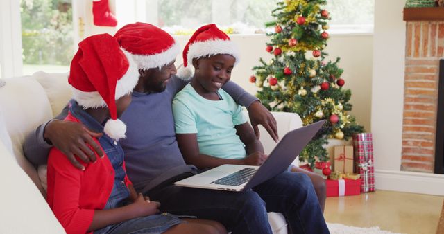 Family in Santa hats using laptop by Christmas tree - Download Free Stock Images Pikwizard.com