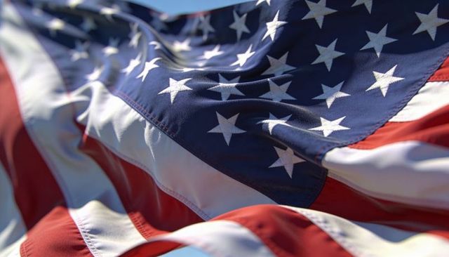 Sunlit american flag billowing in wind showing stars, stripes and fabric texture