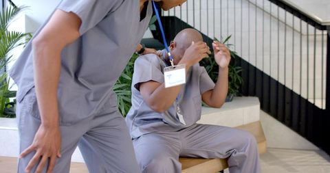 African american male healthcare staff comforting fatigued colleague in hospital lobby