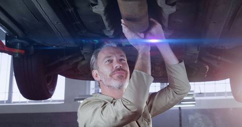 Mechanic Working Under Vehicle with Light Trails
