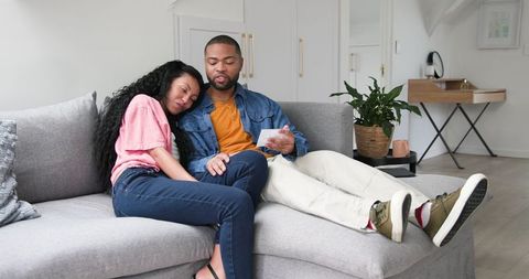 Excited couple celebrating pregnancy with ultrasound scan on sofa