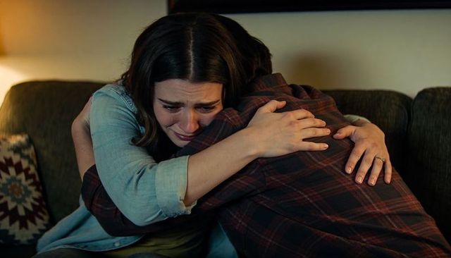 Comforting embrace between tearful woman and partner on couch conveying emotional support