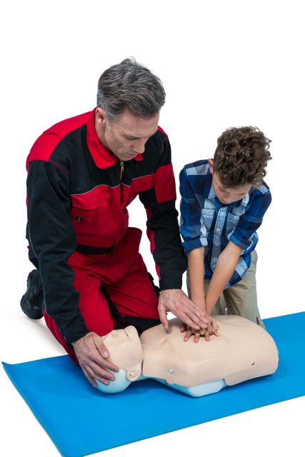 Paramedic training cardiopulmonary resuscitation to boy against white background