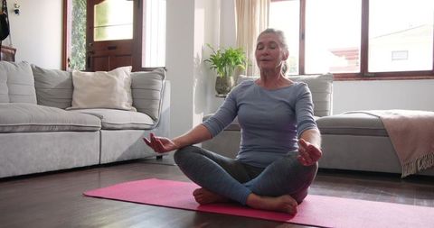 Senior Woman Meditating on Yoga Mat in Cozy Living Room