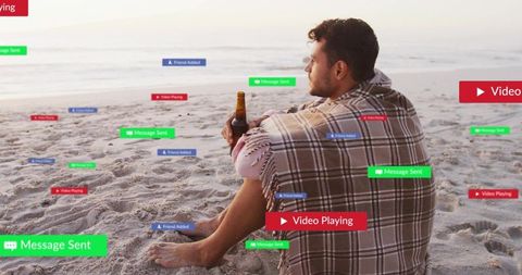 Man Relaxing on Beach with Digital Notifications During Sunset