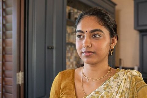 Traditionally elegant indian woman in kitchen with tile backsplash