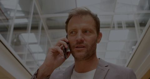 Businessman Discussing Deals on Smartphone in Modern Office