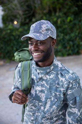 Military man smiling outdoors with backpack