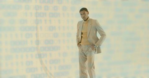 Man in Beige Suit with Binary Code Projection and Wristwatch