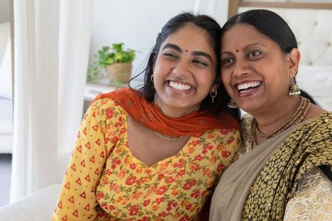 Smiling indian mother and daughter embracing at home