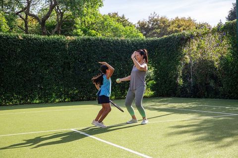 Mother and Daughter Sharing Fun on Tennis Court High-Fiving