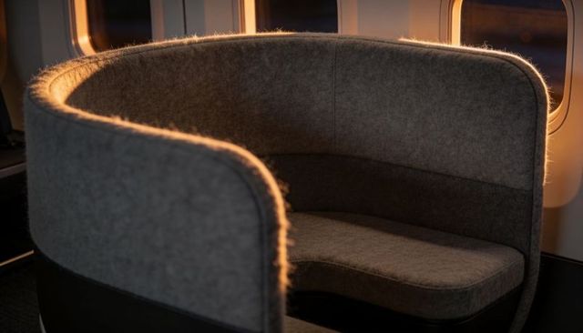Sunset rim light bathing curved high-back banquette in premium aircraft cabin lounge interior