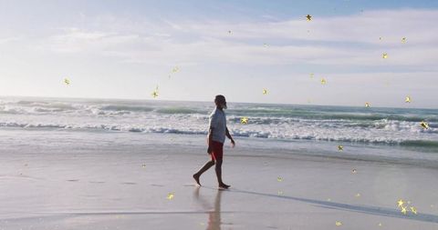 Person strolling on serene beach with reflective wet sand