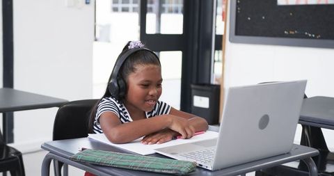 Young Student Learning with Laptop and Headphones in Classroom
