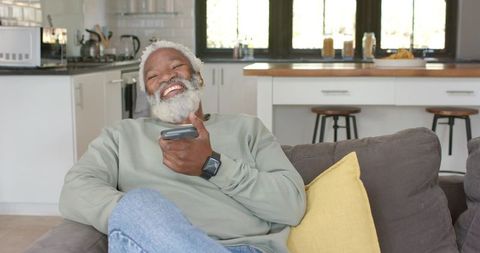 Senior man relaxing with tv remote in cozy home environment