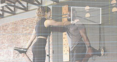 Partner quad stretch in industrial gym with brick wall and functional training rig