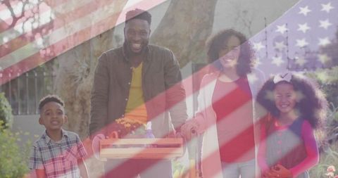 Happy family gardening together in sunlit yard under usa flag