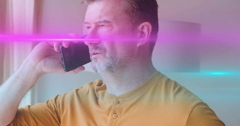 Mature man talking on smartphone by window with cinematic pink and cyan light streaks