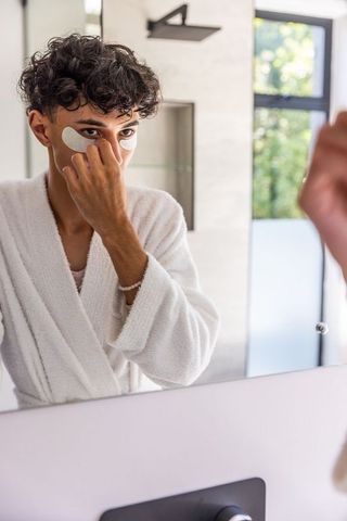 Man Applying Under-Eye Patches in Modern Bathroom