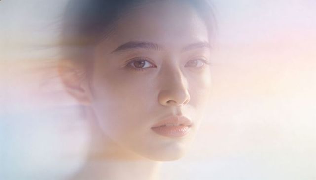 Ethereal pastel closeup gazing female model with soft lens flare and dreamy glow