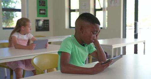 Diverse students using tablets in classroom, focused digital learning moment