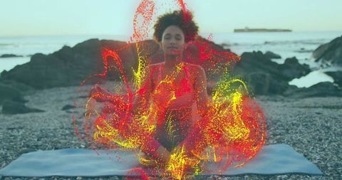 Woman Meditating with Vibrant Energy Particles on Pebble Beach