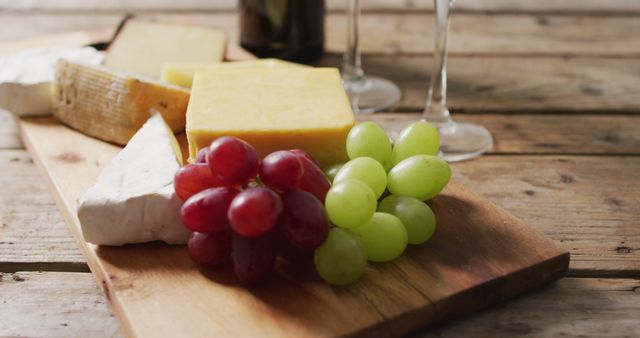 Image of diverse cheeses, grapes and glasses of wine on wooden surface. food, appetizers and party concept.