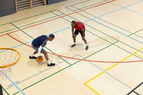 Two players dribbling one-on-one on indoor court during basketball training and defense drill