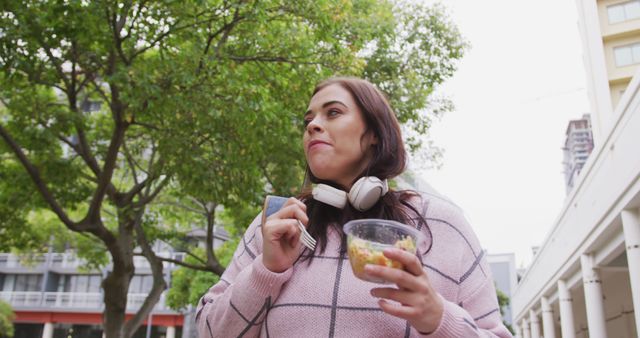 Young Woman Enjoying Salad While Listening to Music Outdoors - Download Free Stock Images Pikwizard.com