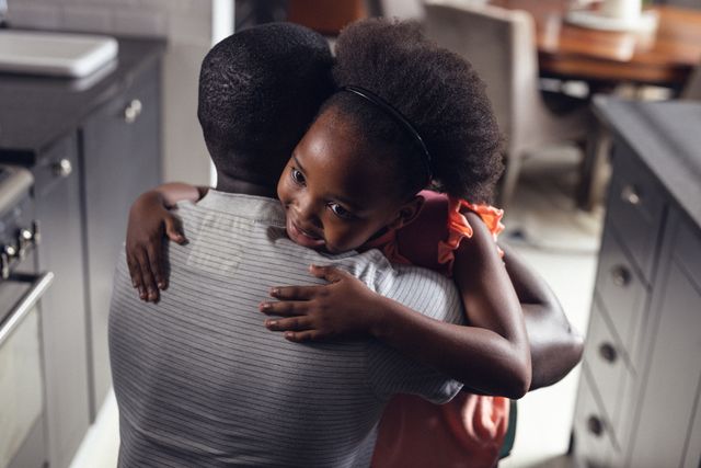 Rear view of african american affectionate father embracing happy daughter with afro hair at home. Unaltered, family, love, togetherness, childhood, lifestyle and home concept.