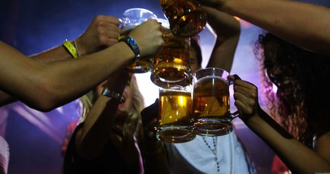 Young Adults Toasting Beer Mugs at Vibrant Party Celebration