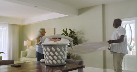 Senior Couple Folding Laundry Together in Modern Living Room